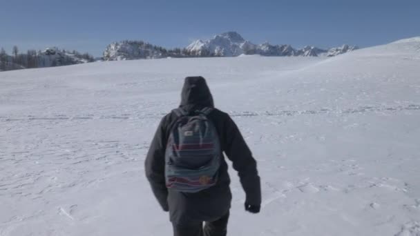 Περιστρεφόμενη βολή ενός πεζοπόρου που περπατάει σε ένα χιονισμένο χωράφι — Αρχείο Βίντεο