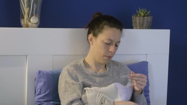 Девушка с коронавирусом измеряет температуру и высморкается — стоковое видео