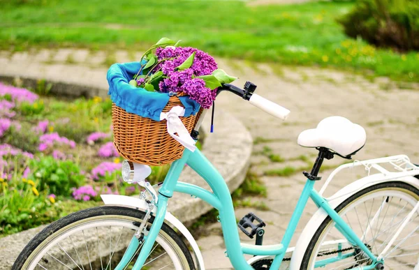 Turquoise bicycle with a basket of flowers.Basket with purple lilac