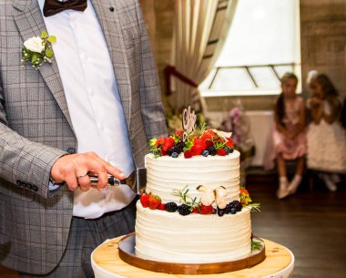 Gelin ve damatlı düğün pastası. Beyaz masasında güller olan büyük beyaz düğün pastası.