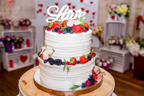 Wedding cake with bride and groom.big white wedding cake with the roses on a white table