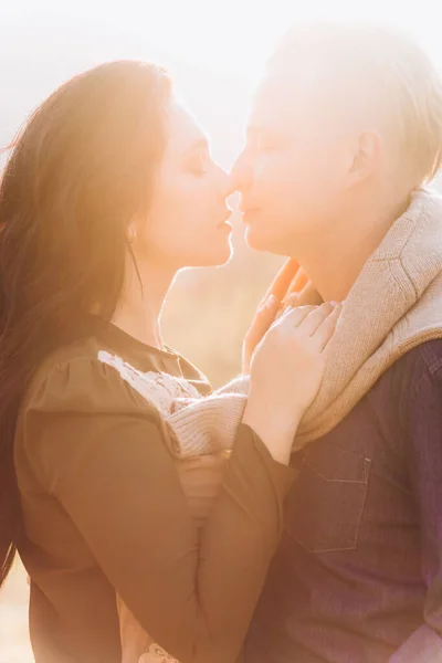 Casal amoroso ao pôr-do-sol. Namorado elegante e namorada beijar uns aos outros . — Fotografia de Stock