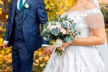 Düğün buketi gelinin elinde. Damat ve gelin el ele tutuşun.. 