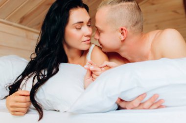 Erkek arkadaşı ve kız arkadaşı beyaz çarşafların üzerinde yatıyor. Genç bir çiftin sabahı. İlişki.