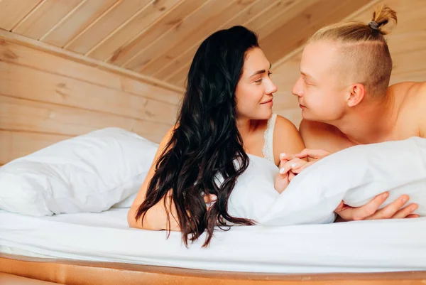 O namorado e a namorada estão deitados em lençóis brancos. Manhã de um jovem casal. Relação . — Fotografia de Stock