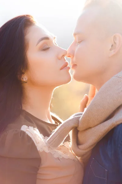 Casal amoroso ao pôr-do-sol. Namorado elegante e namorada beijar uns aos outros . — Fotografia de Stock