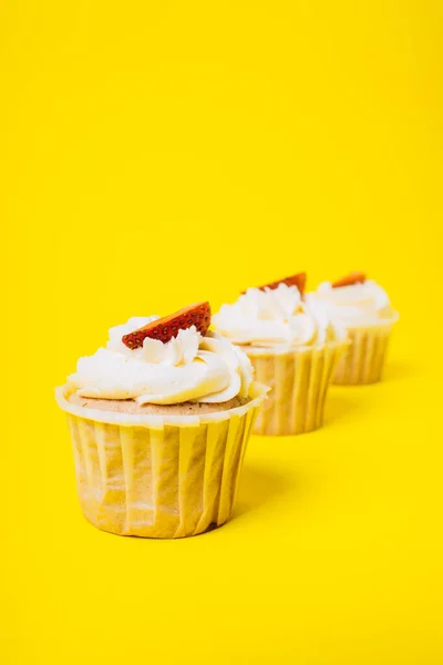 Sarı arka planda beyaz kremalı ve çilekli kekler. Pişirme ve tatlılar. — Stok fotoğraf