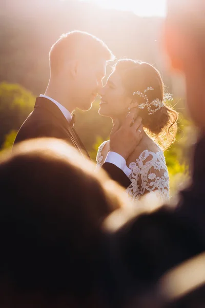 Beijo amor noiva e noivo. Feliz juntos contra o pano de fundo da grama verde e um lago ao pôr do sol. — Fotografia de Stock