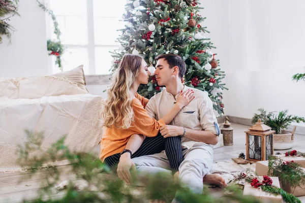 Casal amoroso dá um ao outro presentes para o Natal perto da árvore de Natal . — Fotografia de Stock
