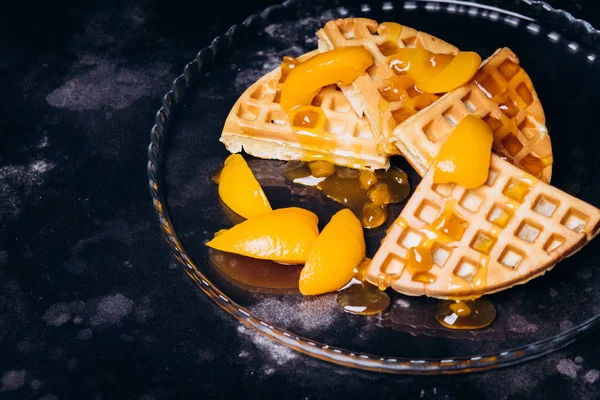 Waffles with peaches for breakfast on a black background. — ストック写真