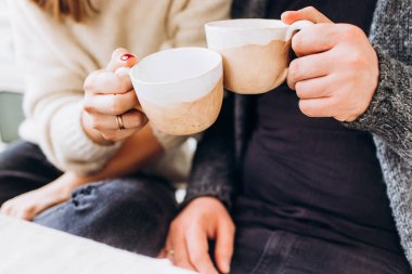 Birbirine aşık bir çiftin ellerinde çay olan iki fincan..