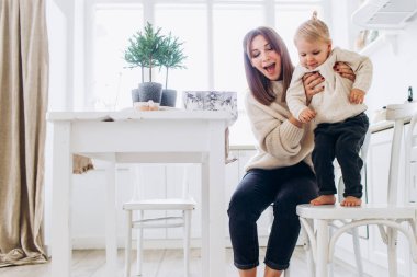 Anne ve kızı parlak bir mutfakta. Homellik. Neşeli bebek ve annesi. 