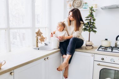 Anne kızını kaşıkla besler. Aile aydınlık mutfakta.. 