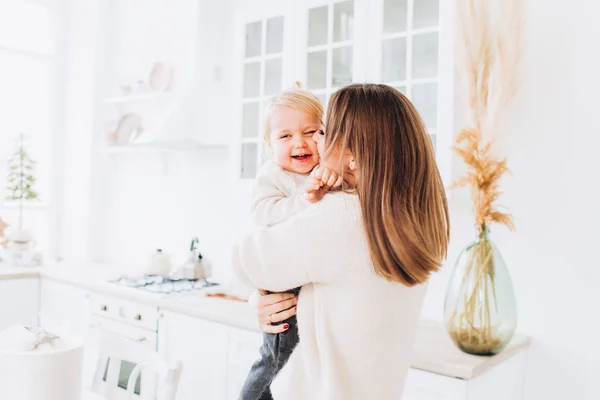 Mother and daughter in a bright kitchen. Homeliness. Joyful baby and his mom. — Stock Photo, Image