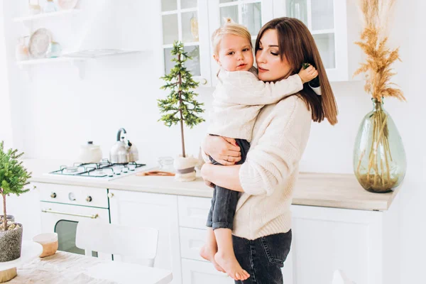 Mor och dotter i ett ljust kök. Hemtrevnad. Glädjande bebis och hans mamma. — Stockfoto