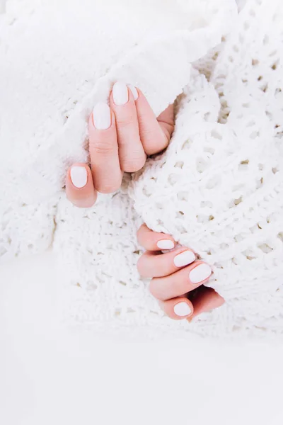 Stylish trendy white manicure. Tender female hands.