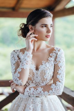 Gelin, yeşil çimlerin ve gölün arkasında beyaz bir gelinlik giyiyor..