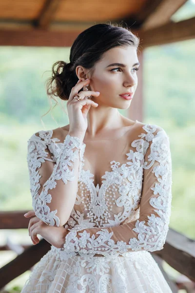 Gelin, yeşil çimlerin ve gölün arkasında beyaz bir gelinlik giyiyor..