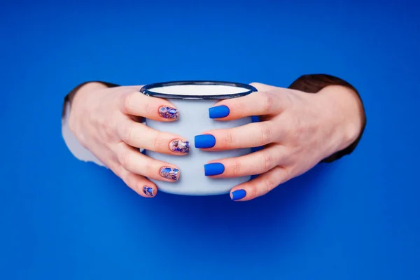 Manicure matte azul em um fundo azul com óculos azuis redondos . — Fotografia de Stock