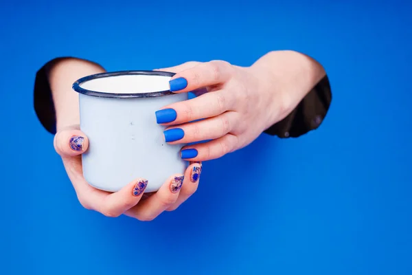 Manicure matte azul em um fundo azul com óculos azuis redondos . — Fotografia de Stock