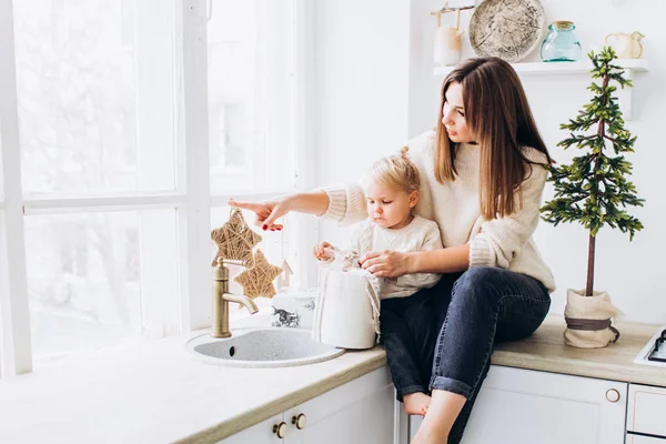 Mom and daughter in the kitchen in a bright apartment or house. — Stock Photo, Image