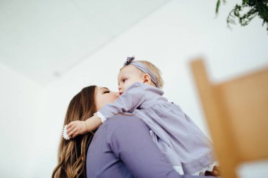 Anne gülümser ve kızını öper. Mutlu bir aile. Bir annenin portresi..