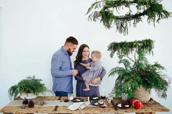 Family in blue clothes happily play with a child.