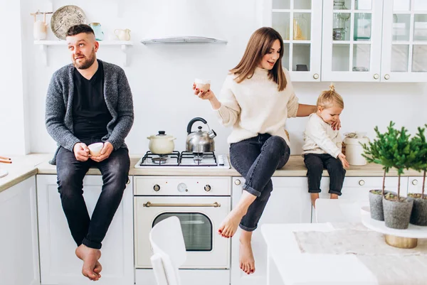 Happy family of three in a bright kitchen smiling. — Stockfoto