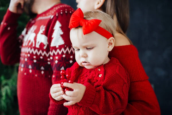 Family in red sweater clothes happily play with a child.