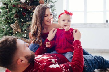 Kırmızı kazaklı aile bir çocukla mutlu bir şekilde oynuyor..