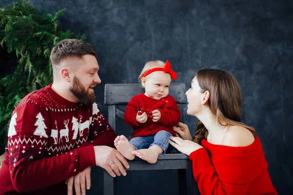 Rodina v červeném svetru líbat podpatky dítěte. — Stock fotografie