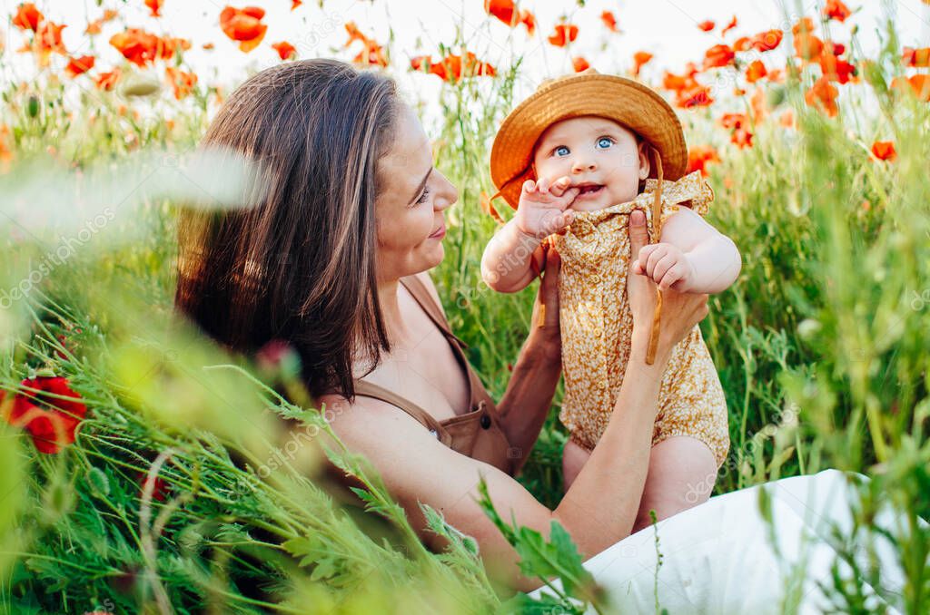 Mother with daughter in a flowering meadow of red flowers.