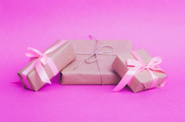 Parşömene sarılı hediyeler, eko kağıtlar, pembe arka planda kraft kağıtları..