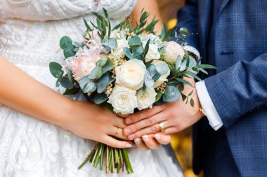 Düğün buketi gelinin elinde. Damat ve gelin el ele tutuşun.. 