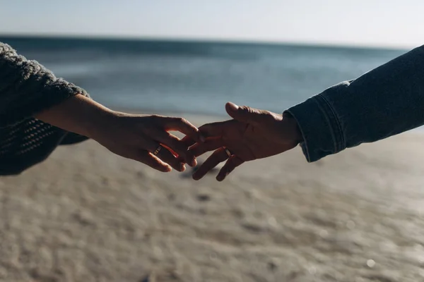 Mãos de um casal contra o fundo do mar esticar um para o outro . — Fotografia de Stock