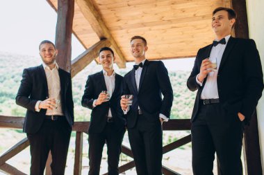 Damat ve arkadaşları düğünü kutluyor ve içki içiyorlar. Takım elbiseli adamlar. Erkeklerin duyguları ve dostluğu.