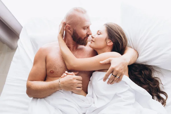 Loving couple in bed on white sheets. Stay at home.