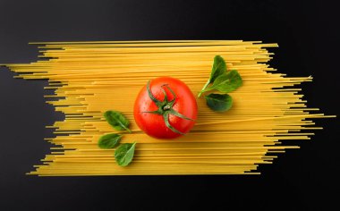 Siyah arka planda spagetti, domates ve ıspanak kompozisyonu. Sağlıklı beslenme konsepti. Üst görünüm