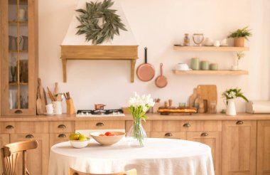 Vazoda bir buket bahar çiçeği ve mutfak masasında meyve. Parlak Trj İskandinav tarzı mutfak