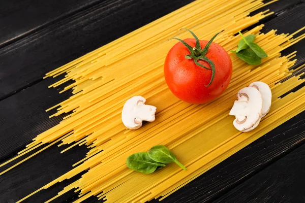 意大利面 西红柿 菠菜叶和蘑菇在黑木背景 意大利菜 素食主义者烹调的概念 — 图库照片