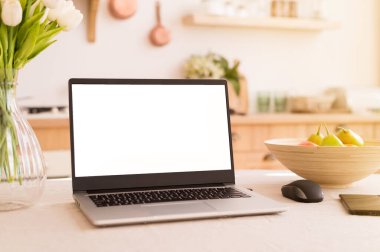 Karantina sırasında parlak bir mutfakta bir iş yeri. Mesajlar için yeri olan bir dizüstü bilgisayar. Telgraf işi. Serbest çalışıyorum. Masada çiçekler ve meyveler.