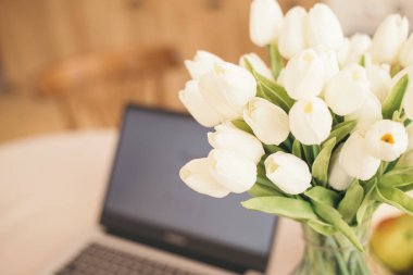 Karantina sırasında parlak bir mutfakta bir iş yeri. Mesajlar için yeri olan bir dizüstü bilgisayar. Telgraf işi. Serbest çalışıyorum. Masada çiçekler ve meyveler.
