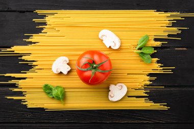 Domatesli spagetti, mantar ve siyah arka planda ıspanak. Üst Manzara. Sağlıklı beslenme konsepti. Ürünlerin Hazırlanması