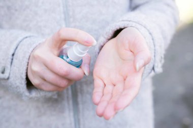 Sokakta antiseptik kullanan bir kız. Yaklaş. Bahar. Sağlık hizmeti konsepti. Koronavirüs ve gribin önlenmesi