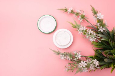 Çiçekli pembe bir arka planda el kremi. Güzellik ve cilt bakımı kavramı.