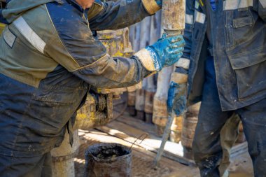 Offshore petrol kuyusu işçisi kuyu başındaki petrol kuyusunda delik açmak için alet ve ekipman hazırlayın. Sondaj borusu bağlantısı kuruyorum. Tribünlerin arasından matkap borusu bağlantısı için bir görünüm