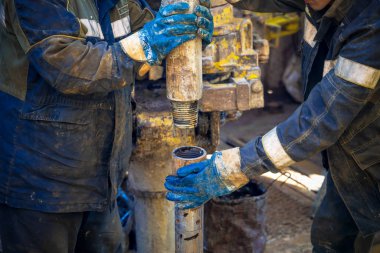 Offshore petrol kuyusu işçisi kuyu başındaki petrol kuyusunda delik açmak için alet ve ekipman hazırlayın. Sondaj borusu bağlantısı kuruyorum. Tribünlerin arasından matkap borusu bağlantısı için bir görünüm