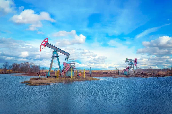 Olje- och gasindustrin. Arbete med oljepump jack på ett oljefält. Moderna pumphackar drivs av en prime mover. — Stockfoto