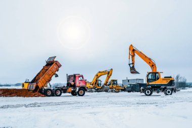 Kazı makinesi kazıları kamyona yüklüyor. Kazı makineleri ağır inşaat ekipmanlarıdır. Dönen platformda patlayıcı, kepçe ya da sopa, kova ve taksiden oluşur.