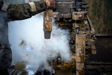 Offshore petrol kuyusu işçisi kuyu başındaki petrol kuyusunda delik açmak için alet ve ekipman hazırlayın. Sondaj borusu bağlantısı kuruyorum. Tribünlerin arasından matkap borusu bağlantısı için bir görünüm